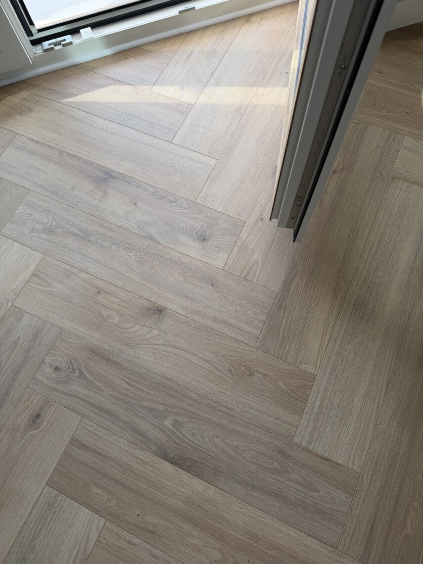Wykończenie paneli laminowanych w jodełkę przy przejściu drzwiowym